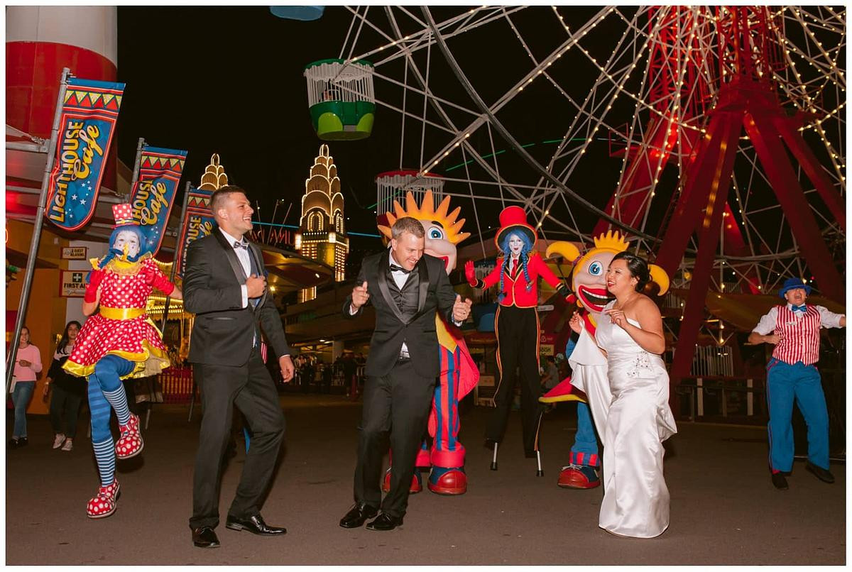 The bridal party is enjoying dancing with the Luna Park characters at Luna Park Sydney.